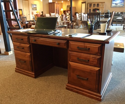 Executive desk with a laptop and papers on top in a showroom