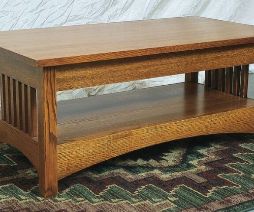 Light stained wooden coffee table with spindles on the ends sitting on a carpet