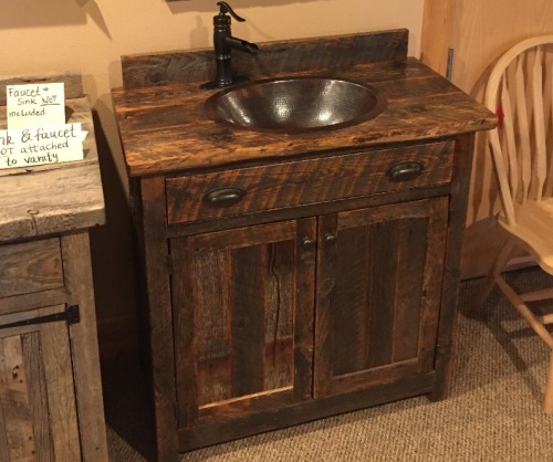 Dark brown stained wooden powder room vanity installed under a mirror with a flush sink and dark finishes