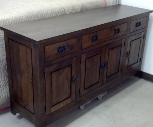  Dark stained buffet with four cabinet doors and 4 drawers sittings against a wall