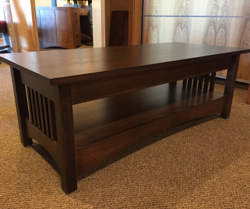 Light stained wooden coffee table with spindles on the ends sitting in a home