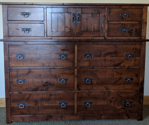 Large wooden chest with a dark stain, black hardware and 4 smaller drawers on top with 6 larger drawers on bottom